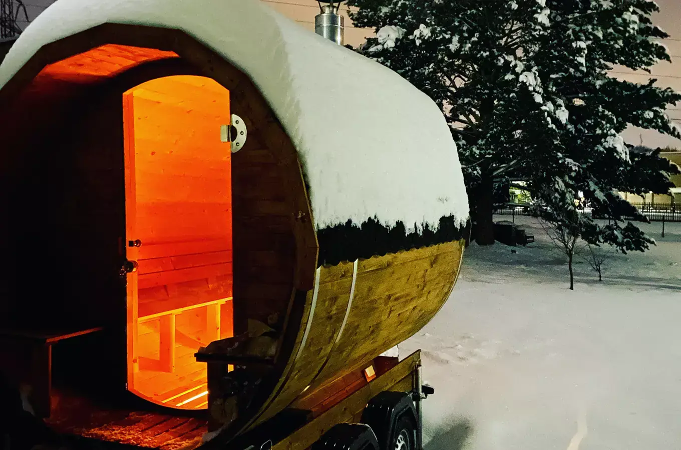 Mobilní sauna v zasněžené noci, uvnitř svítí teplé světlo